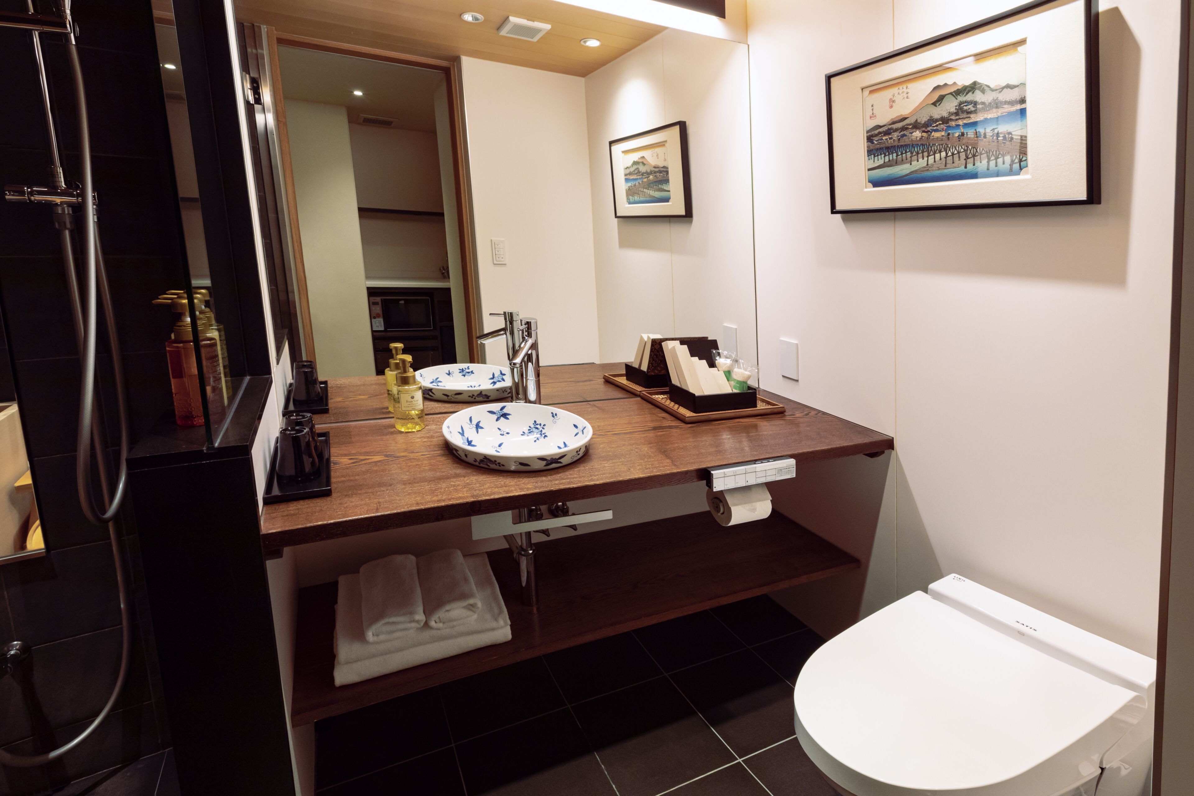A modern bathroom with a wooden vanity, a white toilet, and a framed picture on the wall.
