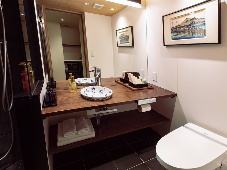 A modern bathroom with a wooden vanity, a white toilet, and a framed picture on the wall.