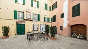 A courtyard with outdoor seating, a bicycle, and a building with a green door labeled "SURREALE". - Sibilla Luxury Flat in center town (Lucca)