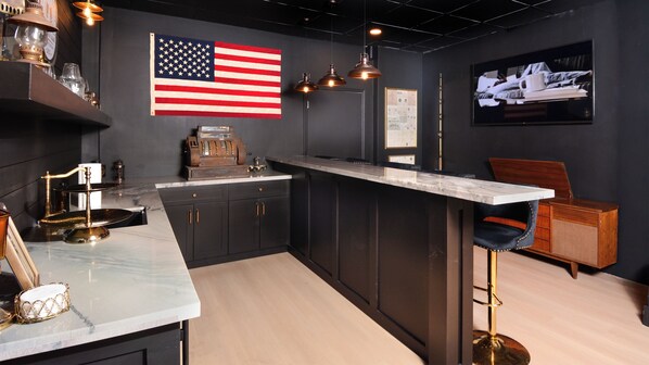 A modern kitchen with a marble countertop, dark cabinetry, and an American flag.