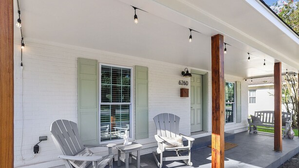 Une véranda avec deux fauteuils Adirondack, une petite table et une boîte aux lettres.