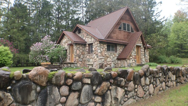 A stone house with a sloped roof and a stone wall in front. - Cozy Countryside Stone House & Pub with 20 acres of outdoor fun! (Morley)