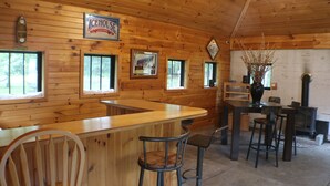 A wooden interior with a bar area, wooden walls, and a fireplace. - Cozy Countryside Stone House & Pub with 20 acres of outdoor fun! (Morley)