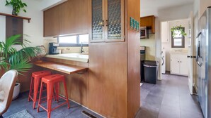 A modern kitchen with wooden cabinets, a bar area, and red stools.