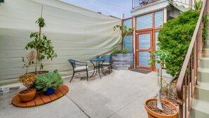 A patio area with potted plants, a small table, and two chairs.