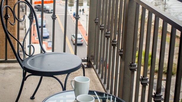 Un balcón con una mesa y una silla, con vista a un río y un puente.
