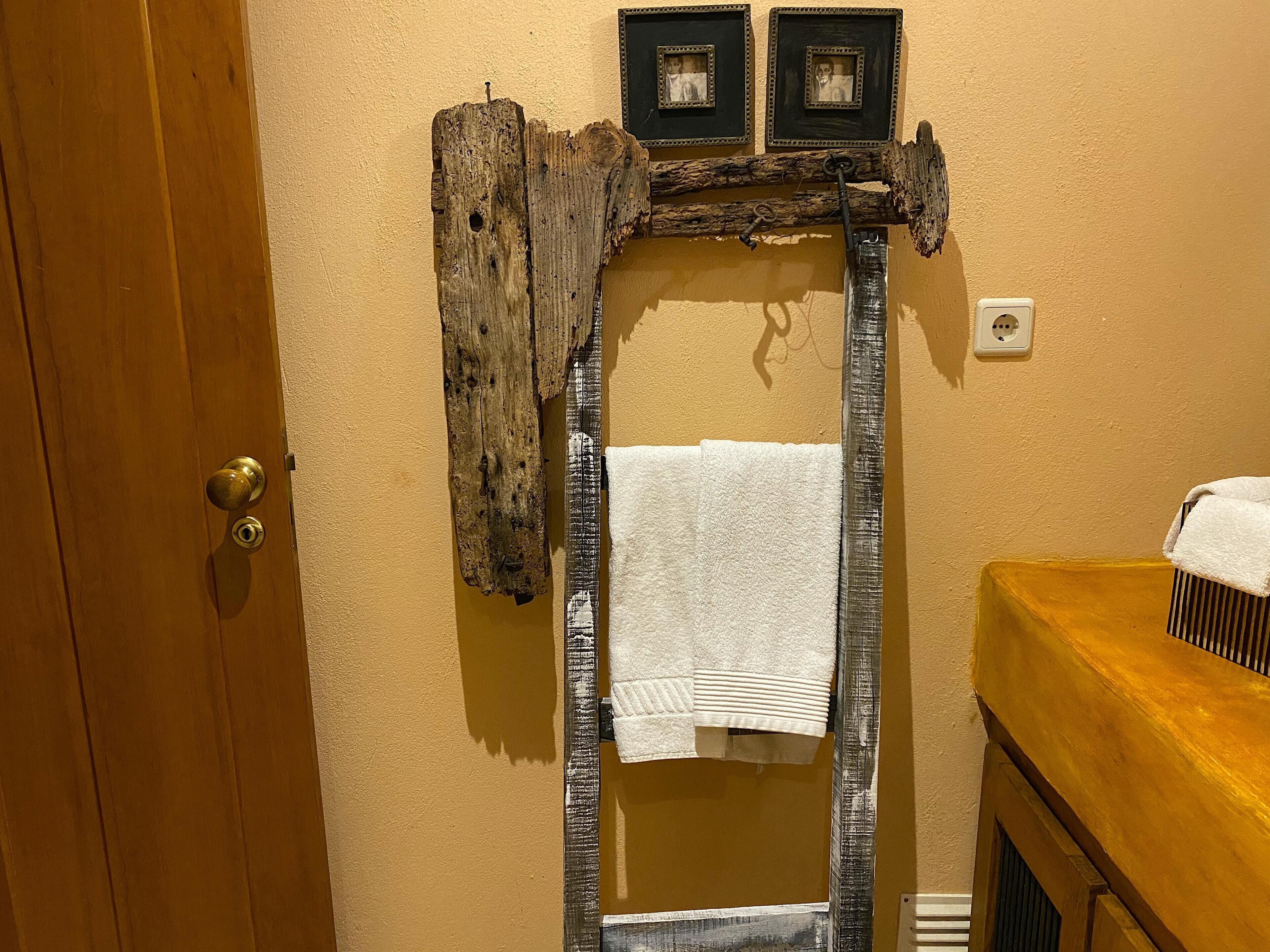 A bathroom with a wooden door, a towel rack with two framed photos, and a white towel hanging on the rack.