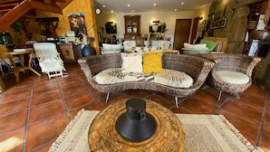 A cozy living room with a wicker sofa, a coffee table, and a rustic stone wall. - Stunning Country Side House with swimming pool (Penafiel)