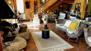 A cozy living room with wicker furniture, a stone coffee table, and a rustic staircase. - Stunning Country Side House with swimming pool (Penafiel)
