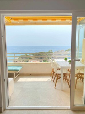 Enjoy ocean views from this balcony with a table, chairs, a single bed, and a potted plant.