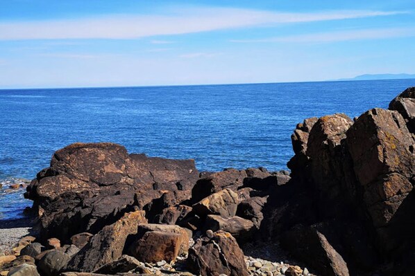 A rocky shoreline with large boulders and a clear view of the ocean.