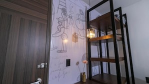 A room with a wooden door, a wall with abstract drawings, a shelf with a vase, and a hanging light fixture. - Casa Sofía (Atlacomulco)