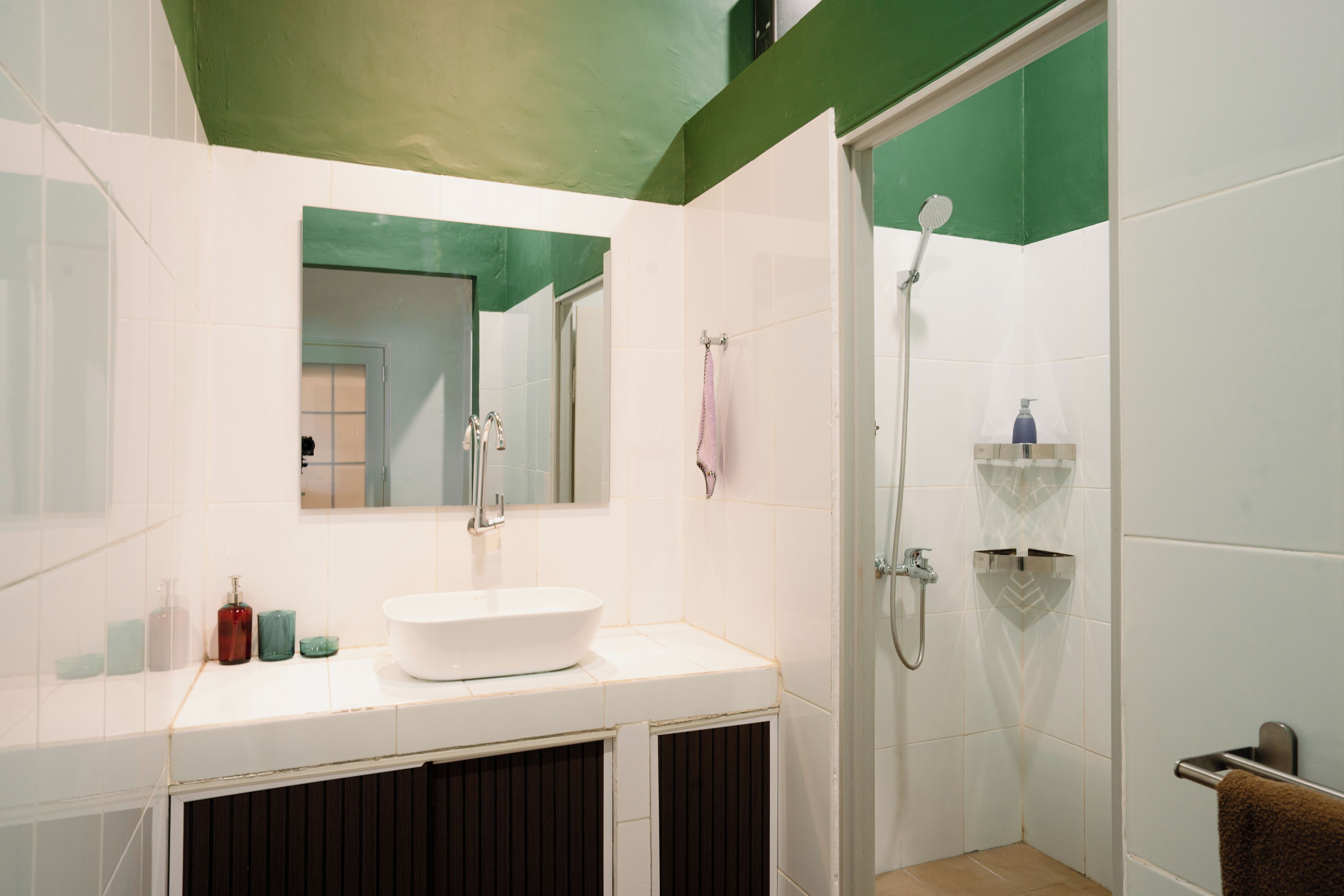 Un baño con lavamanos blanco, espejo y ducha.