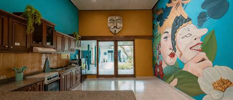 A kitchen with granite countertops, wooden cabinets, and a mural of a woman on the wall.