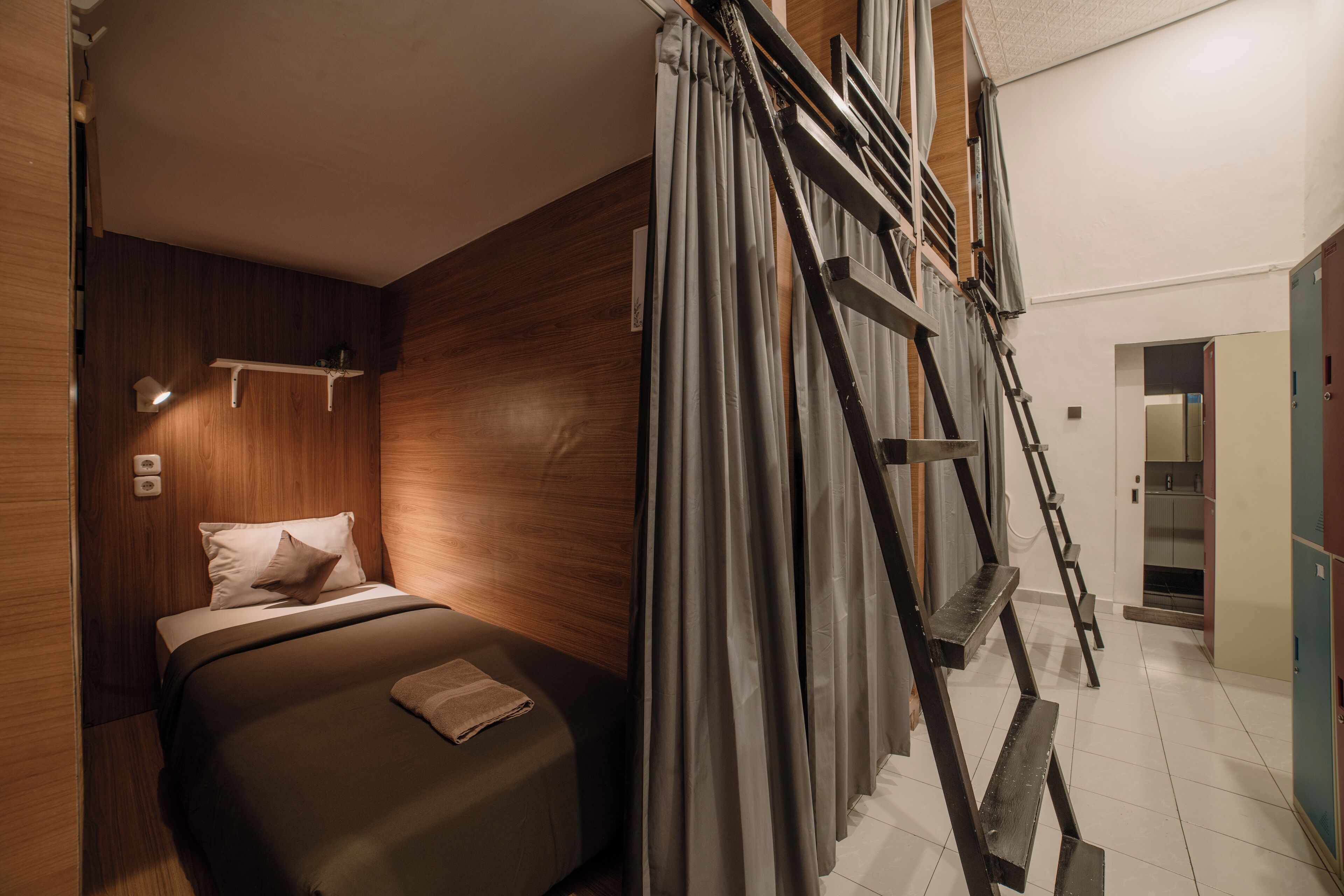 Ein Schlafzimmer mit einem Bett, Holzwänden, einer Leiter und einem im Hintergrund sichtbaren Badezimmer.