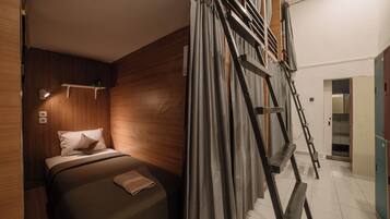 Une chambre à coucher avec un lit, des murs en bois, une échelle et une salle de bain visible au fond.