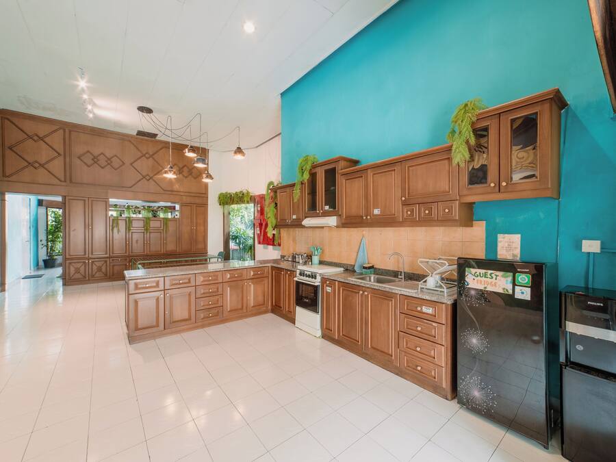 Una cocina amplia con armarios de madera, una isla grande y electrodomésticos modernos, incluyendo un refrigerador y un horno.