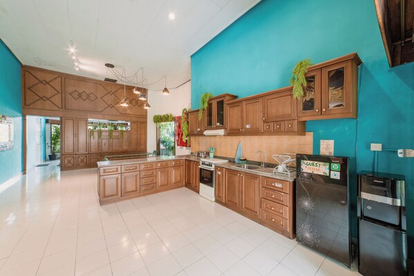 Una cocina amplia con armarios de madera, una isla grande y electrodomésticos modernos, incluyendo un refrigerador y un horno.