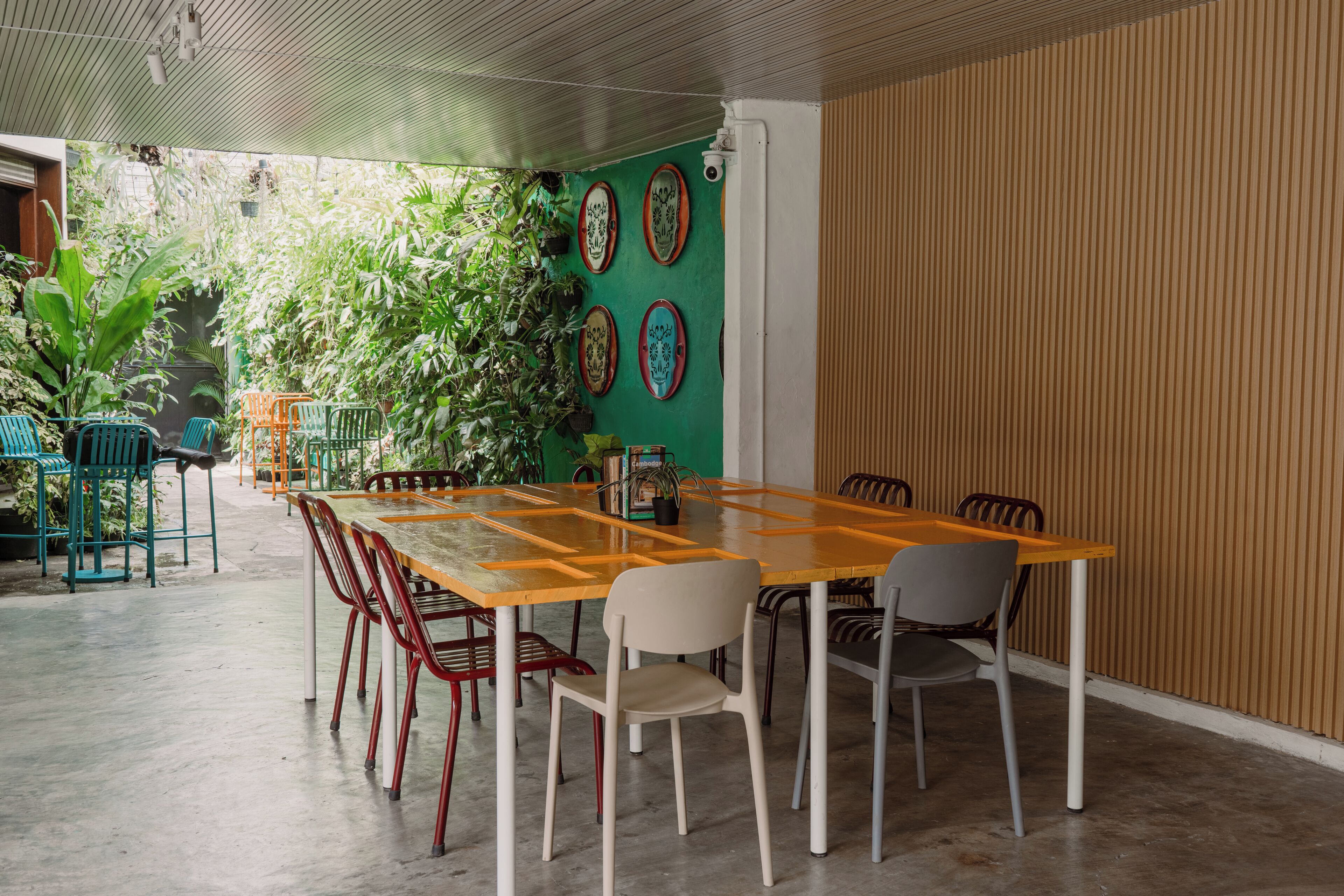 Un coin repas avec une table et des chaises en bois, entouré de plantes vertes et agrémenté d’assiettes décoratives accrochées au mur.
