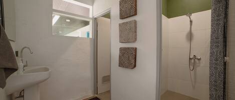 A bathroom with a sink, a shower, and decorative wall art.