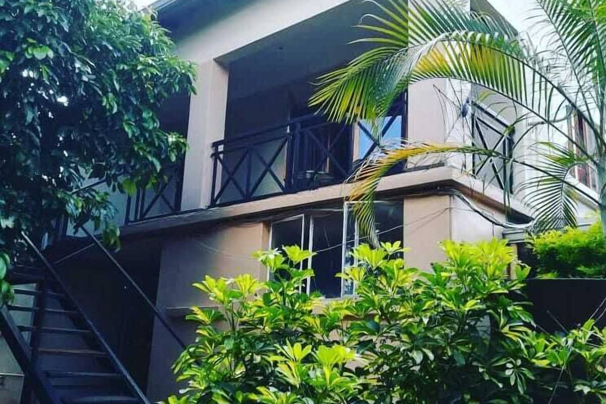 Un edificio moderno con balcón, escalera y abundante vegetación.