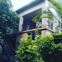 A modern building with a balcony, a staircase, and lush greenery.