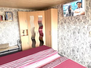A bedroom with a bed, wardrobe, television, and a shelf with books. - Apartment 'Ferienwohnung Beyer Friedrichroda' with Private Terrace, Private Garden and Wi-Fi (Friedrichroda)
