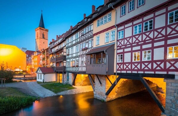 A traditional European town with a river, a bridge, and a church tower.