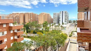 Een hoog appartementencomplex met meerdere balkons, een helder uitzicht op de omgeving en een veraf gelegen waterpartij.