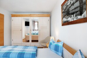 Ein Schlafzimmer mit Bett, Stuhl, Kleiderschrank und einem Gemälde.