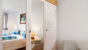 Quarto com cama, mesa de cabeceira, luminária, cadeira e guarda-roupa.