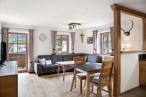 Un salon chaleureux avec un canapé, une table à manger et des chaises, un plafond en bois et une croix accrochée au mur.