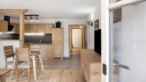 Eine moderne Küche mit Holzausbau, ein Essbereich mit Tisch und Stühlen und eine sichtbare Tür zu einem anderen Raum.