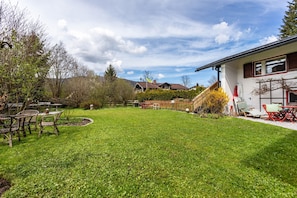 A well-maintained backyard with a lawn, outdoor furniture, and a house with a white exterior and red accents.