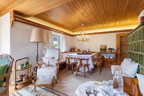 Un coin repas chaleureux, avec des meubles en bois, un lustre et un buffet vert.