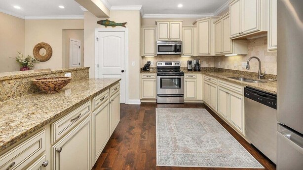 A kitchen with granite countertops, stainless steel appliances, and cream-colored cabinetry. - Close to Island Amenities (Saint Simons Island)