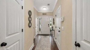 A hallway with white doors, a beige wall, and a patterned rug. - Close to Island Amenities (Saint Simons Island)