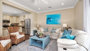 A living room with a sofa, armchairs, a coffee table, and a kitchen in the background. - Close to Island Amenities (Saint Simons Island)