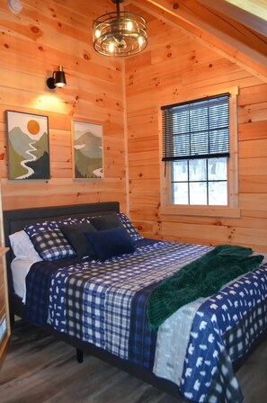 Quarto de cabana de madeira com cama, janela e decoração nas paredes.