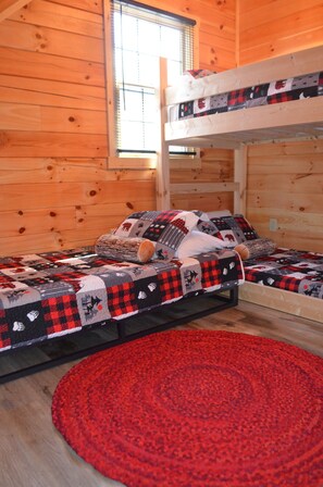 A bunk bed room with a red rug and patterned bedding.