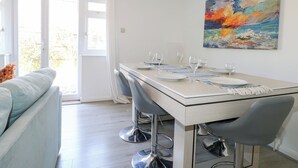 Un comedor con una mesa dispuesta para cuatro, un sofá y un cuadro en la pared.