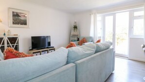 Una sala de estar moderna con un sofá azul claro, un televisor de pantalla plana y un cuadro en la pared.