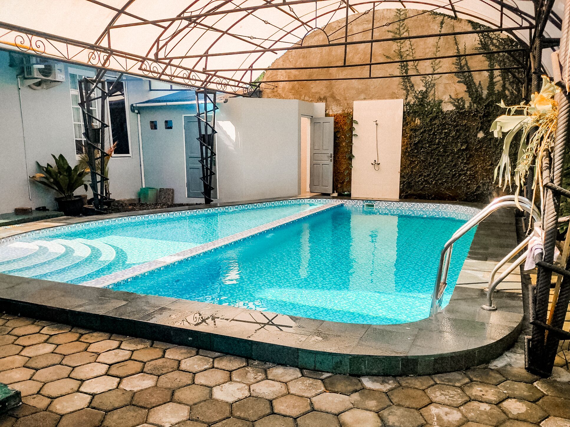 An indoor swimming pool with a tiled floor, surrounded by walls and a glass ceiling.