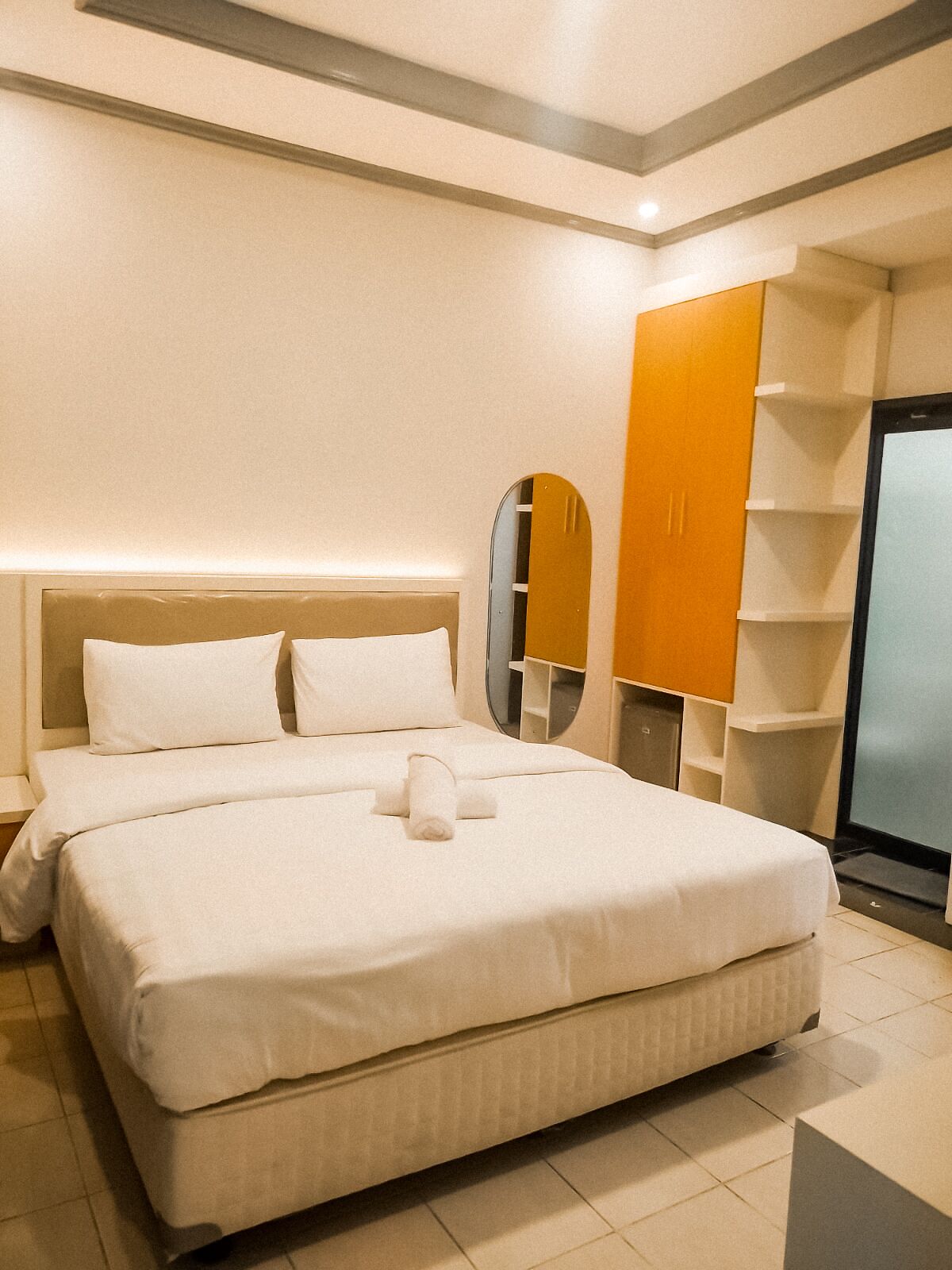 A hotel room with a large bed, a wardrobe, and a mirror.