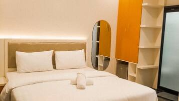 A hotel room with a large bed, a wardrobe, and a mirror.