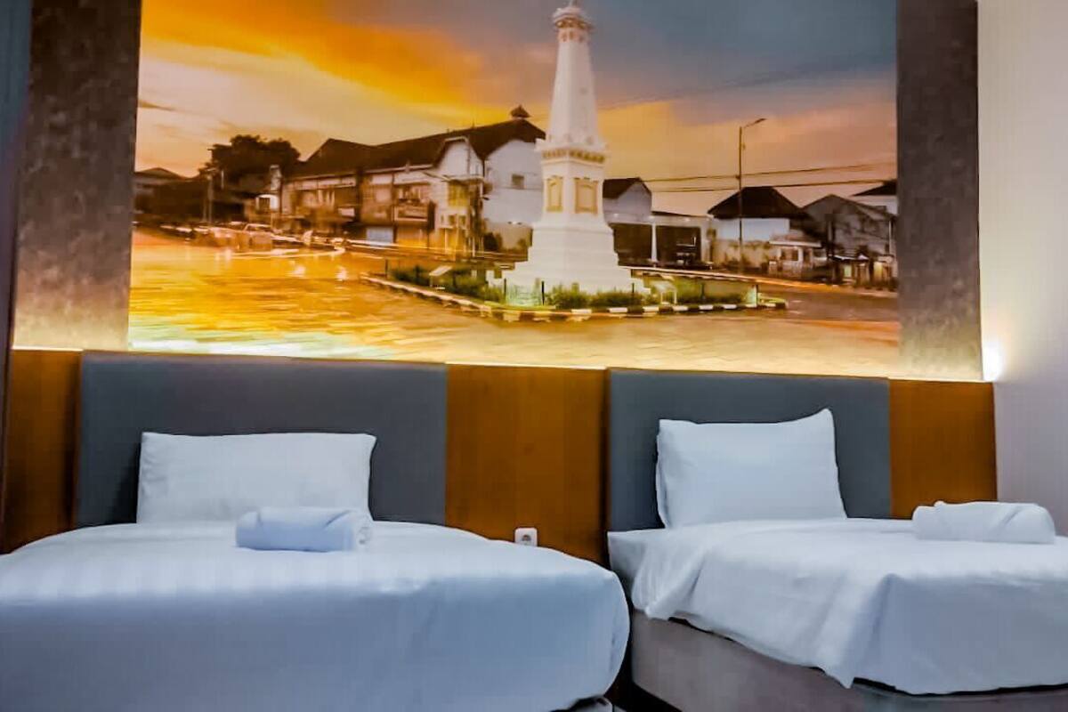 Quarto de hotel com duas camas, um grande mural na parede retratando uma paisagem urbana e uma cabeceira moderna.