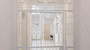 Ein weißes Metallgitter mit aufwendigen Verzierungen und einem kleinen Fenster.