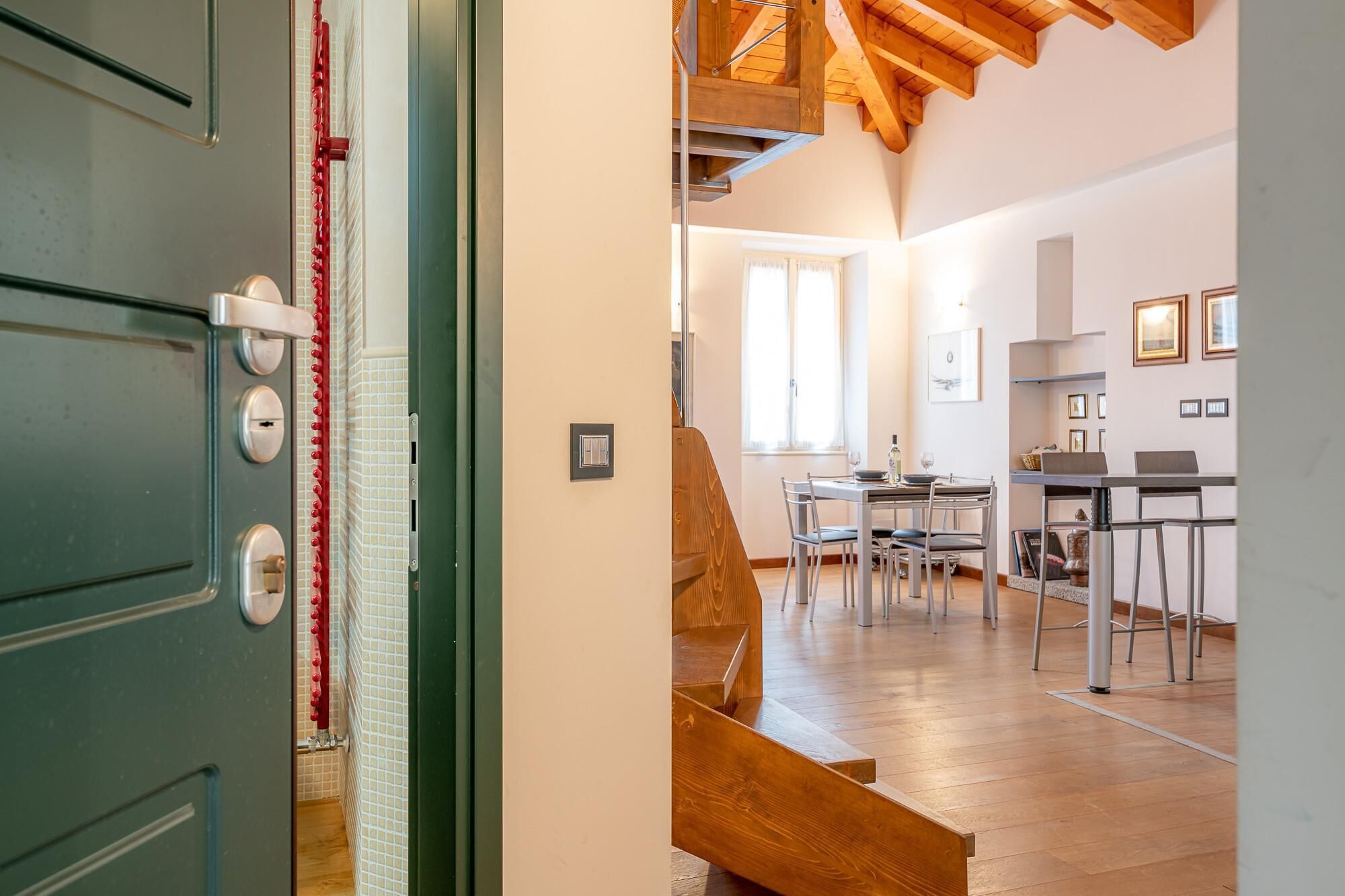 Een moderne keuken met een eethoek, een houten trap en uitzicht op de woonkamer.