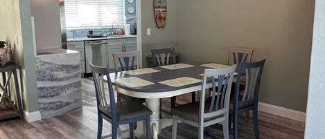 A dining area with a marble countertop, a chandelier, and a kitchen in the background.