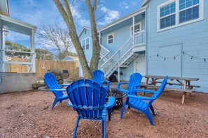 A backyard with blue Adirondack chairs, a fire pit, and a picnic table. - Three Bungalows to Spread out for Large Group or Family (Galveston)